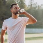 Young sportsman drinking water at stadium